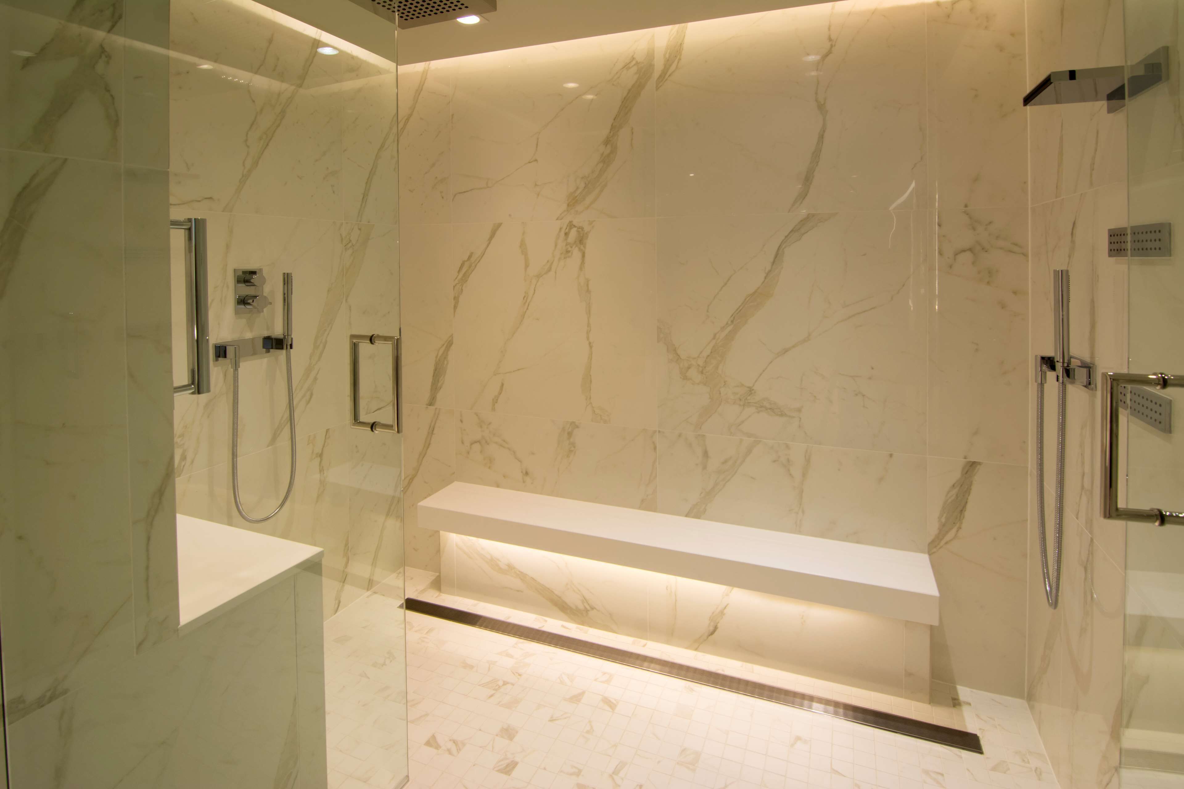 Un baño moderno con paredes de mármol y un banco empotrado.