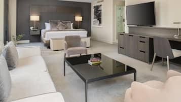 A modern hotel room with a bed, a TV, a desk, and a coffee table.