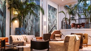 A spacious lobby with a modern design, featuring a large sofa, multiple chairs, a staircase, and large wall murals. - Hotel Theodore Seattle Downtown, Tapestry by Hilton (Seattle)