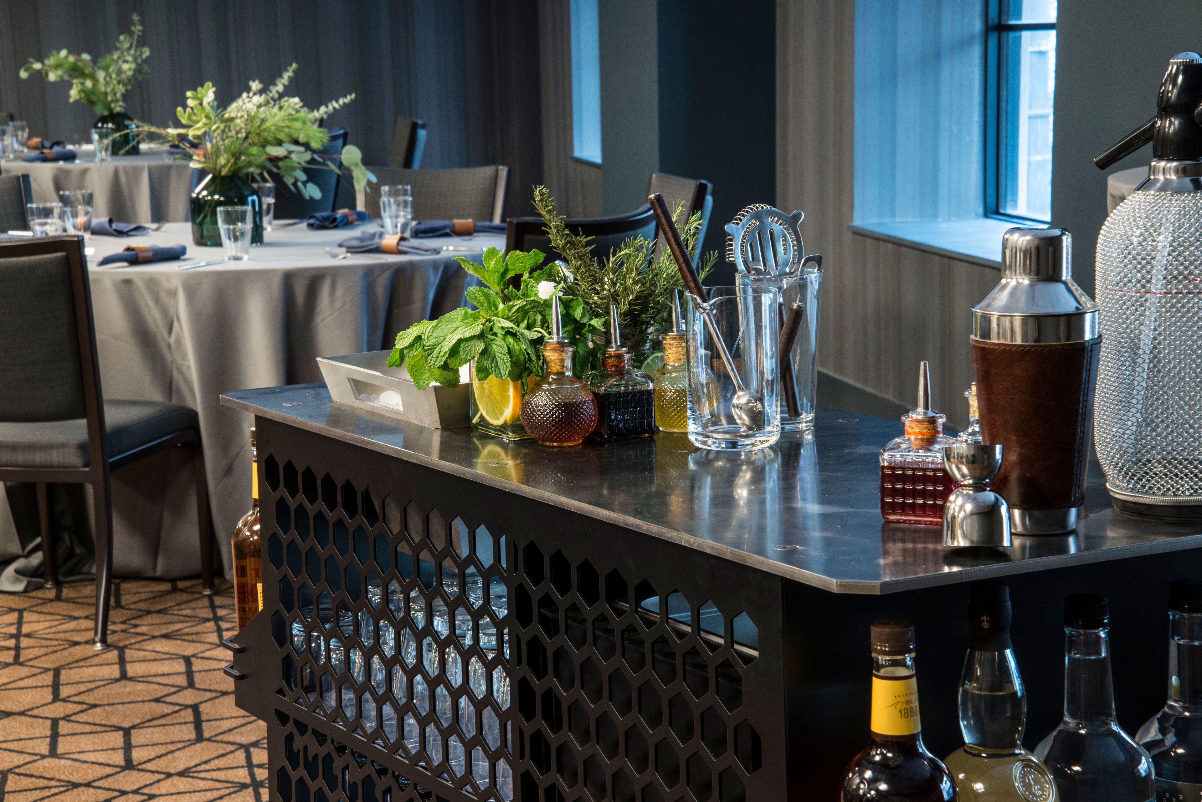 A bar area with a variety of bottles and glasses, a decorative plant, and a window with a view.
