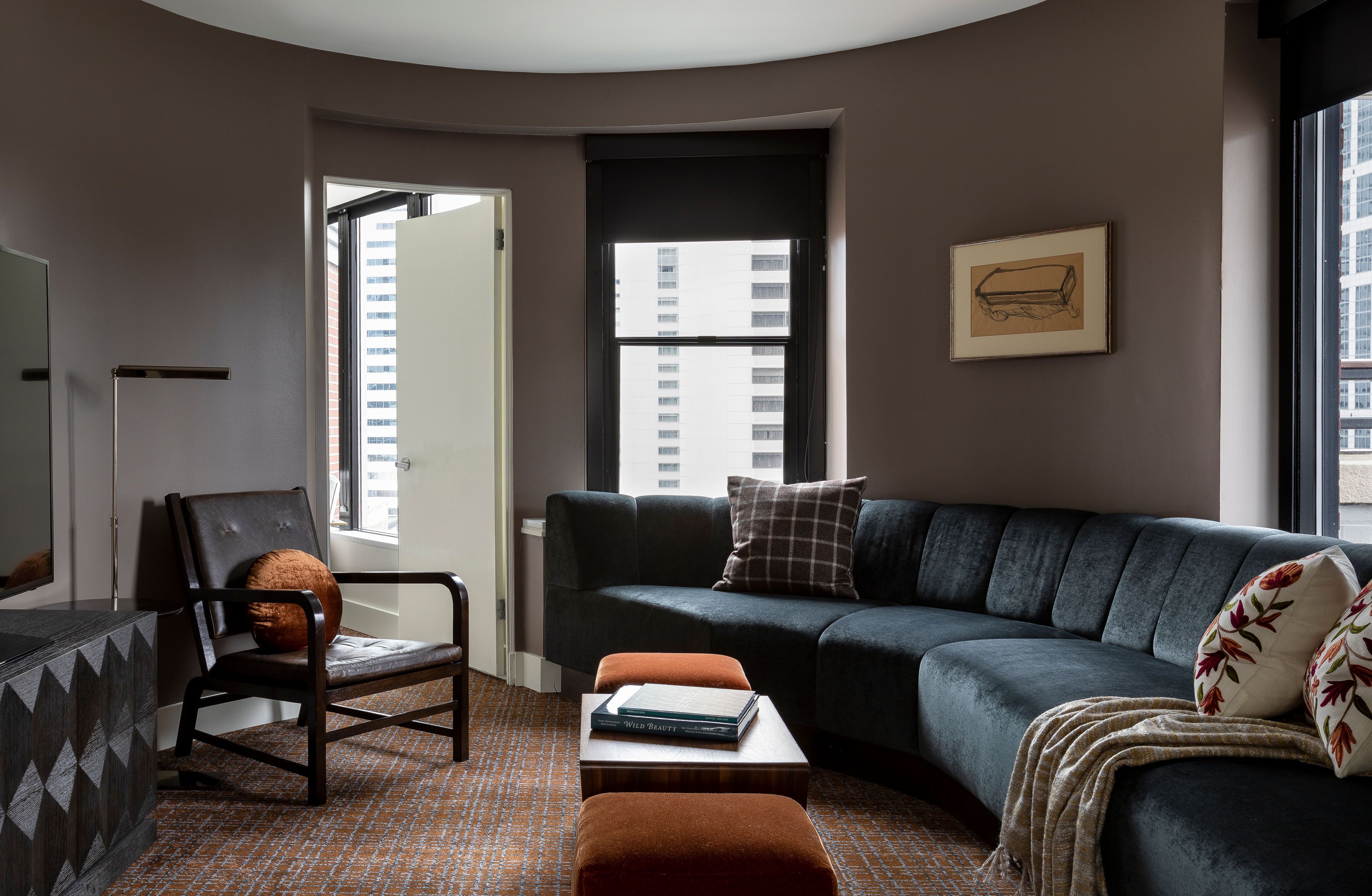 Un salon moderne avec un canapé gris foncé, une chaise en bois, une petite table sur laquelle repose un livre et un sol à motifs.