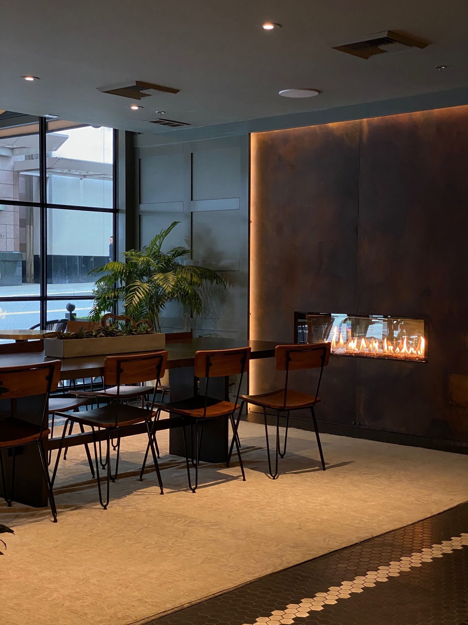 A modern interior with a dining area, a large window, and a wall-mounted fireplace.
