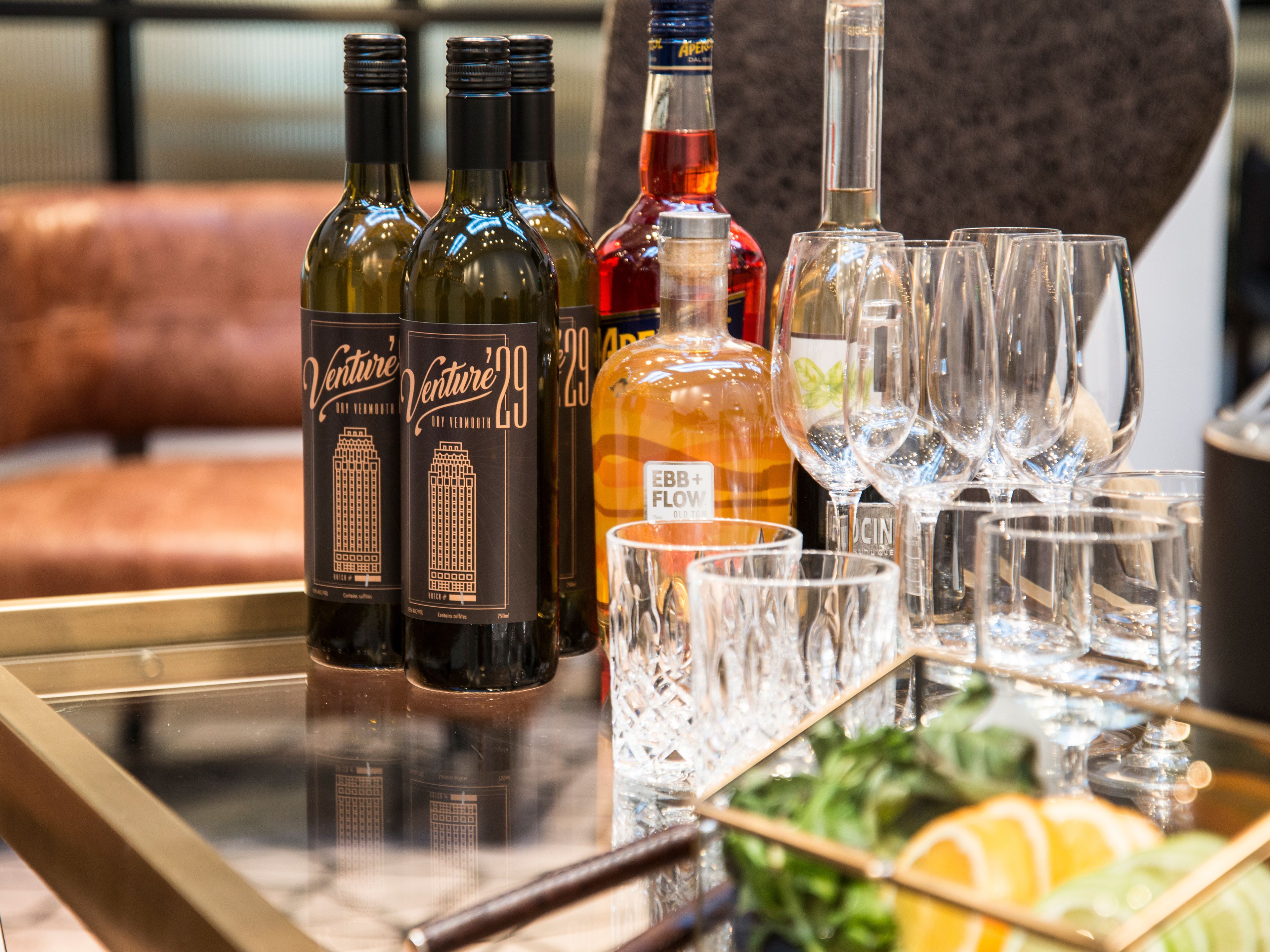 A table with bottles of wine, glasses, and a fruit garnish.
