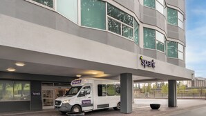 A building with a 'spark' sign, a white van parked in front, and a paved entrance area. - Spark by Hilton Seattle Airport (SeaTac)