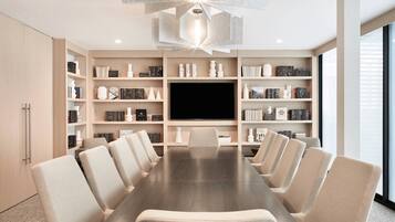 A modern conference room with a long table, multiple chairs, and a large flat-screen TV.