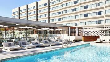 Experience the hotel's modern design and relax by the pool with comfortable lounge chairs and umbrellas.