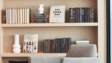 A modern living room with a bookshelf, a grey armchair, and a small side table.