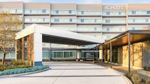 A modern hotel with a covered entrance, multiple floors, and a clear sky.
