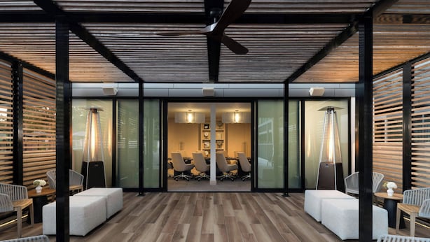 A modern indoor space with a wooden floor, white cushioned seating, and a central table.