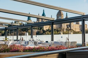An outdoor dining area with tables set for two, overlooking a historic building with domed architecture. - InterContinental Barcelona by IHG (Barcelona)