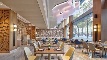 Un interior de restaurante moderno con techos altos, luz natural y diversas opciones de asientos.
