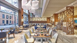 A modern restaurant interior with large windows, contemporary furniture, and a decorative wooden partition. - InterContinental Barcelona by IHG (Barcelona)