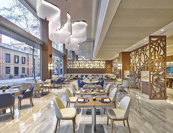 A modern restaurant interior with large windows, contemporary furniture, and a decorative wooden partition. - InterContinental Barcelona by IHG (Barcelona)