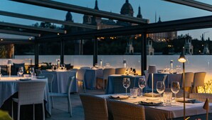 An outdoor dining area with tables set for a meal, overlooking a cityscape with historical buildings. - InterContinental Barcelona by IHG (Barcelona)