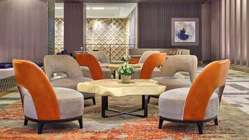 A modern interior with a central seating area featuring four chairs and a table, surrounded by patterned walls and a geometric ceiling design.