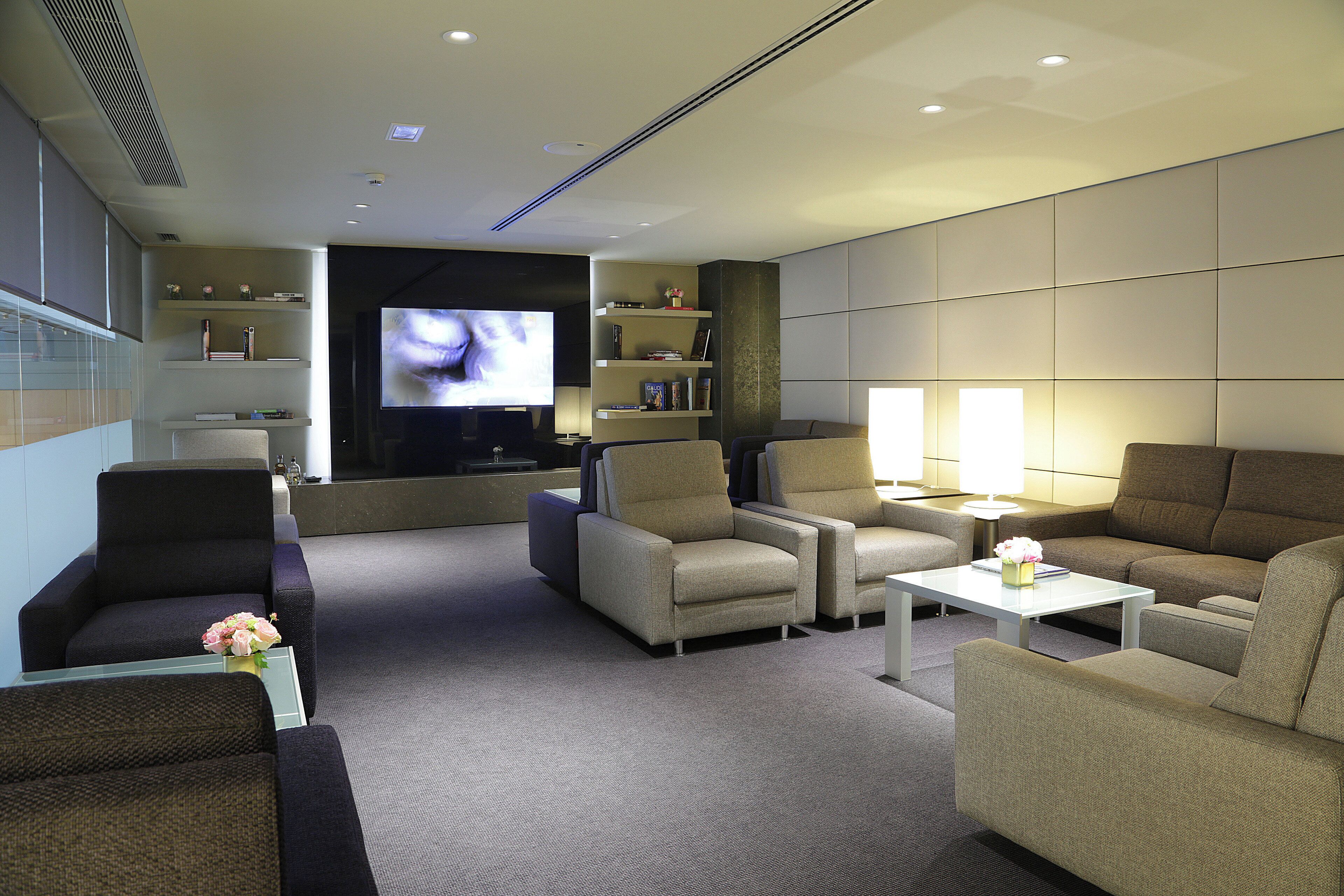 Une chambre d’hôtel moderne équipée d’un téléviseur à écran plat, de fauteuils confortables, d’une table basse et d’une bibliothèque.