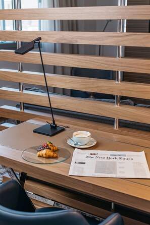 Puisesta penkistä löytyy kannettava tietokone, kahvikuppi, croissant ja sanomalehti.