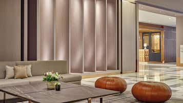 Un lobby moderno con un sofá, una mesa de centro y taburetes decorativos.