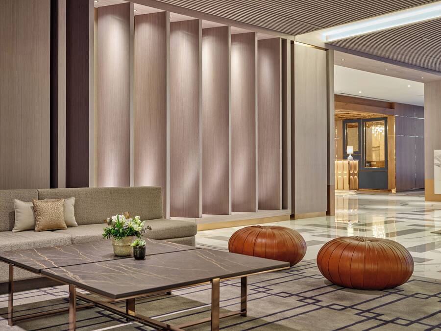 Un lobby moderno con un sofá, una mesa de centro y taburetes decorativos.