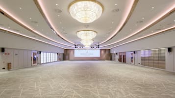 Uma sala de conferências ampla, com uma grande tela exibindo 'INTERCONTINENTAL BARCELONA', lustres e piso estampado.