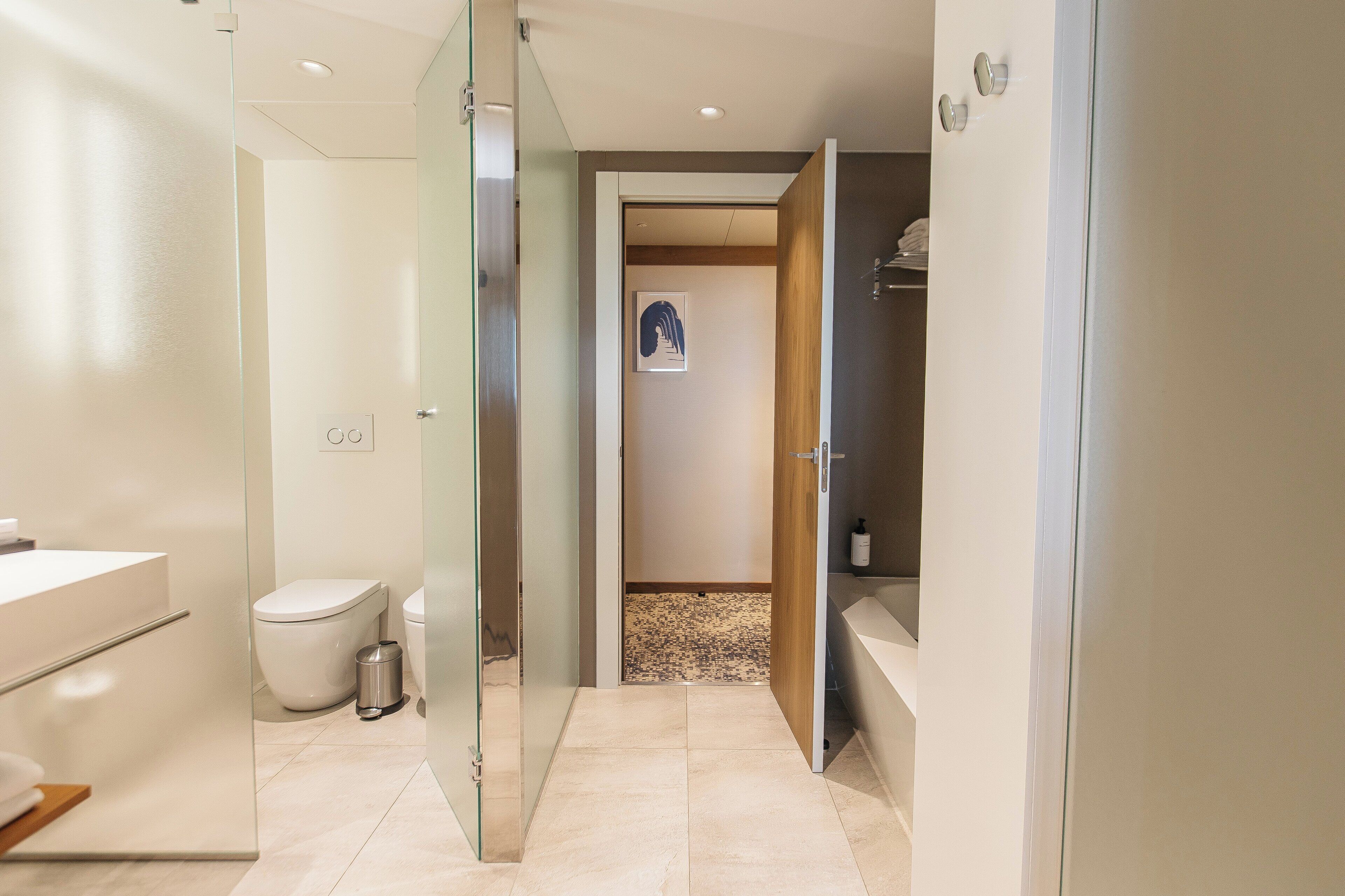 Ein modernes Badezimmer mit Duschkabine aus Glas, einer weißen Toilette und einer Badewanne.