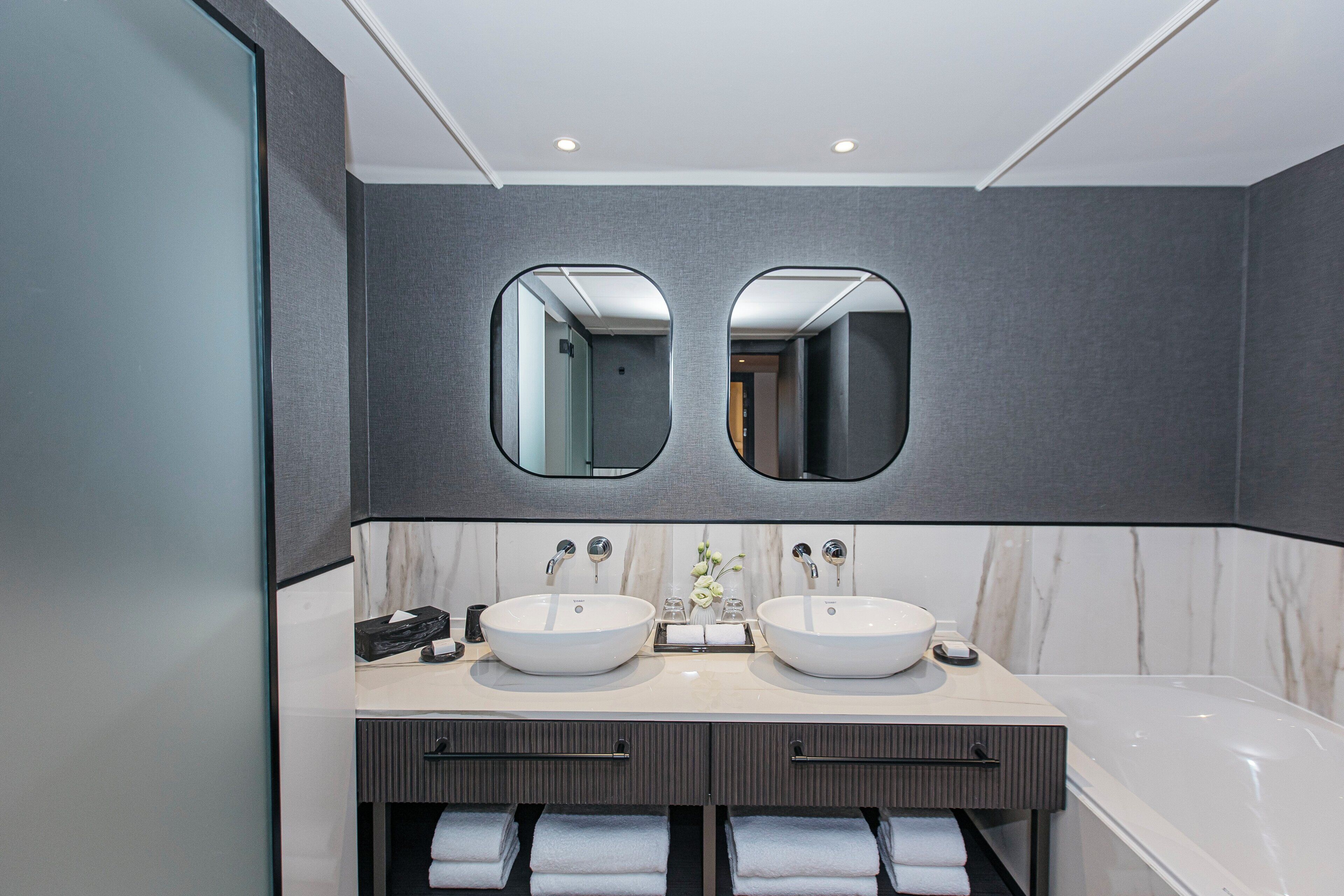 Un baño moderno con dos lavamanos, un espejo grande y una bañera.