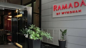 A modern building entrance with a glass door, potted plants, and a sign reading "RAMADA BY WYNDHAM". - Ramada by Wyndham Buenos Aires Centro (Buenos Aires)