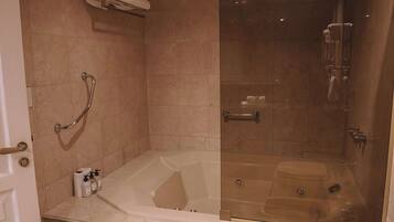 A bathroom with a bathtub, a glass-enclosed shower, and a towel rack.