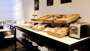 A breakfast buffet with various breads and pastries, a toaster, and neatly stacked plates. - Ramada by Wyndham Buenos Aires Centro (Buenos Aires)