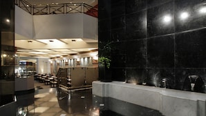 A modern lobby with a marble reception desk, a staircase, and a seating area with tables and chairs. - Ramada by Wyndham Buenos Aires Centro (Buenos Aires)