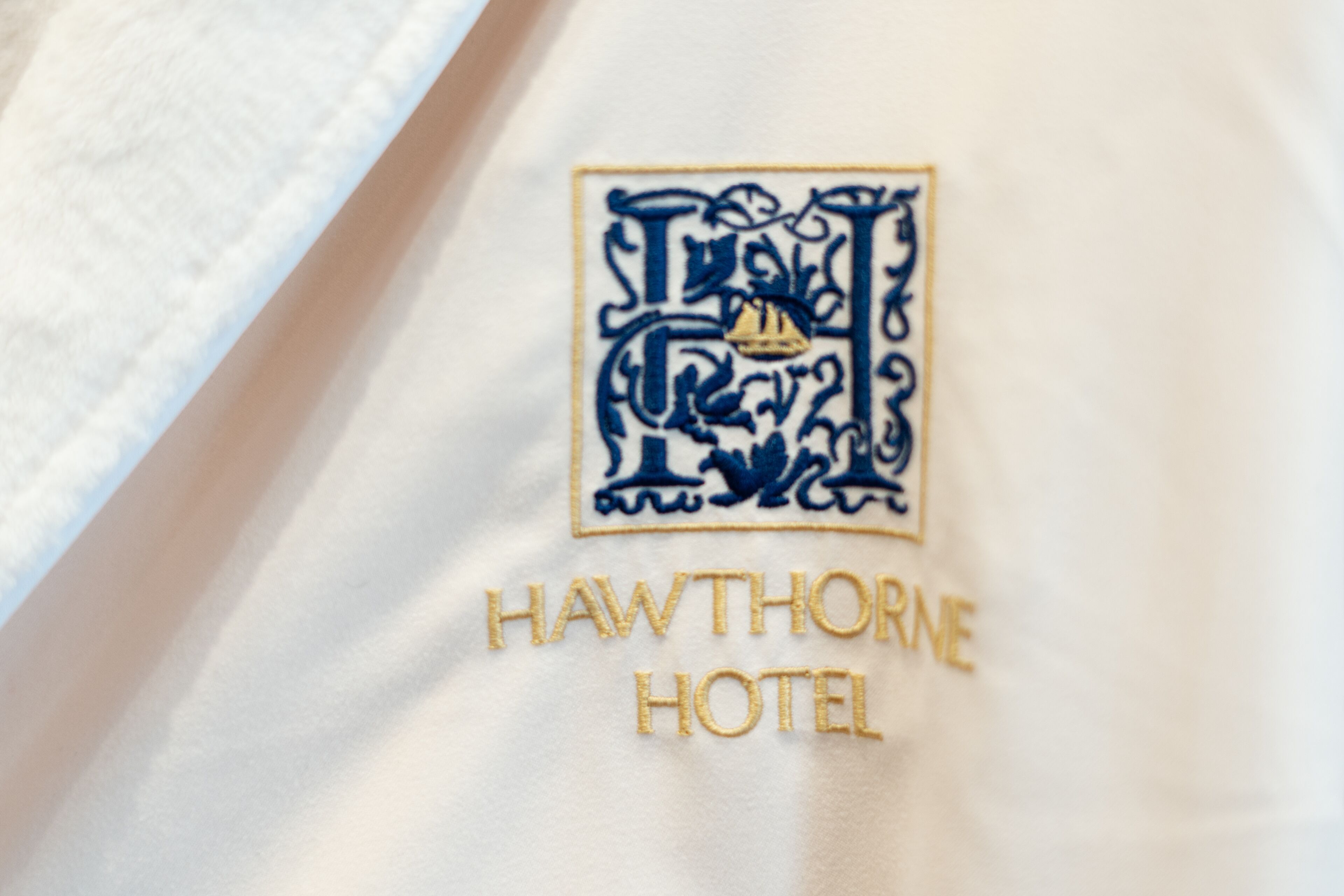 Primer plano del logotipo de un hotel bordado en tela blanca.