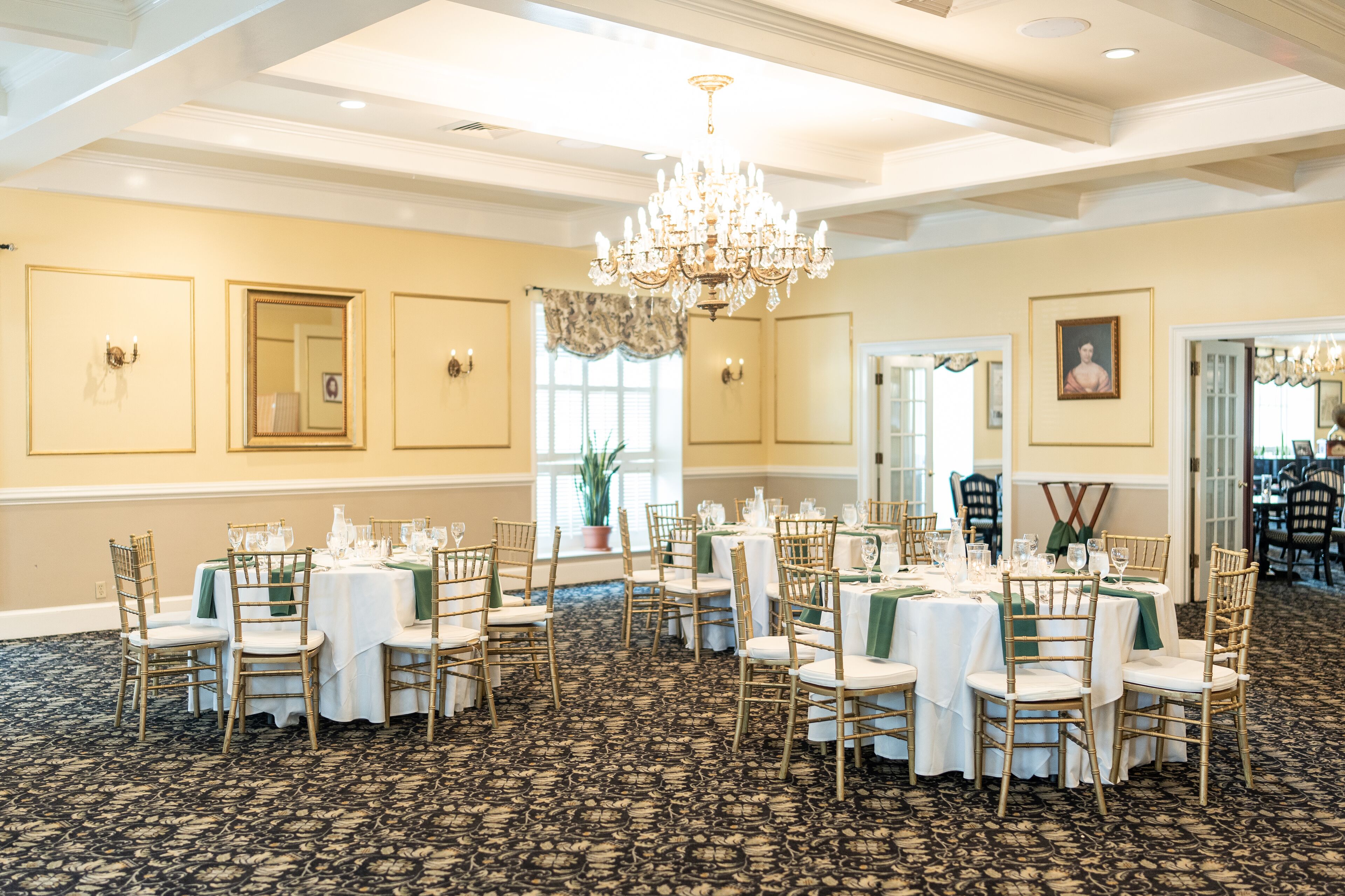 A banquet hall with round tables, chairs, and a chandelier.