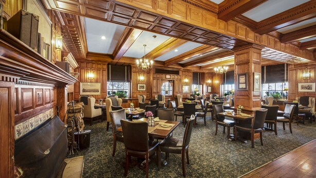 A spacious hotel lobby with wooden paneling, chandeliers, and a variety of seating arrangements including tables and chairs. - Hawthorne Hotel (Salem)