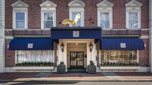 A brick building with a gold eagle statue on the entrance, a QR code on the awning, and a window display with plants. - Hawthorne Hotel (Salem)