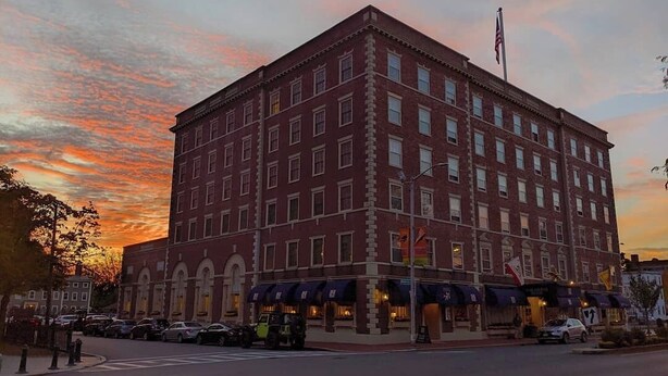 A large brick building with multiple windows and a flag on top.