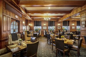 A traditional dining area with wooden paneling, chandeliers, and a patterned carpet. - Hawthorne Hotel (Salem)