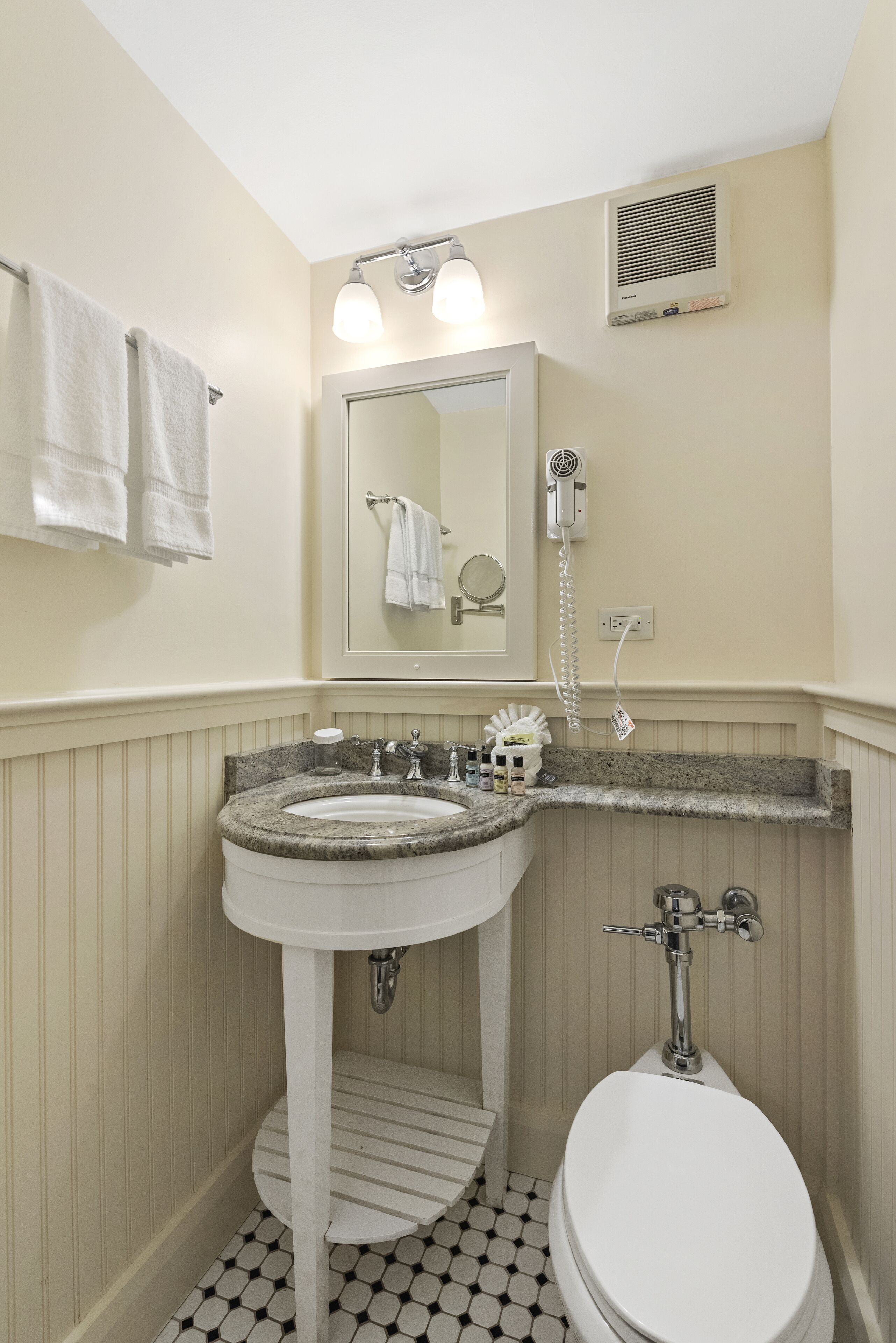 Ein Badezimmer mit Waschbecken, Spiegel, Handtuchhalter und Toilette.