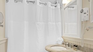 A bathroom with a white sink, a mirror, a towel rack, and a shower curtain.