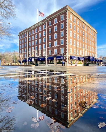 A large brick building with multiple windows and a flag on top.