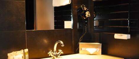 A modern bathroom with a large mirror, a sink, and a towel rack.