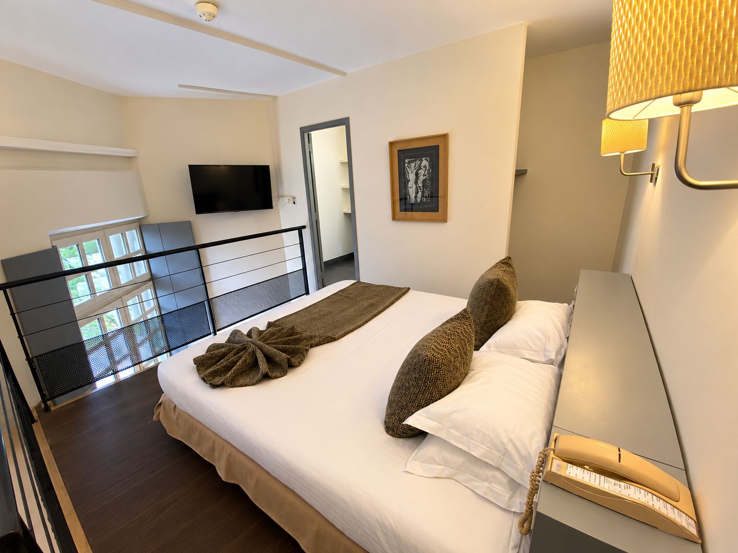 Una habitación de hotel con cama, televisión, un cuadro enmarcado y teléfono.