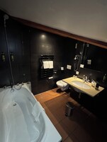 Un baño moderno con bañera, dos lavamanos, inodoro y espejo.