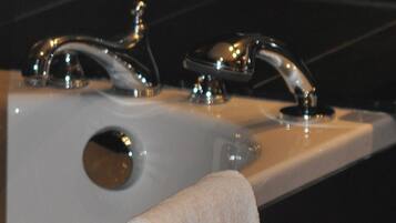 A bathroom with a white bathtub, two chrome faucets, and a white towel hanging on the side.
