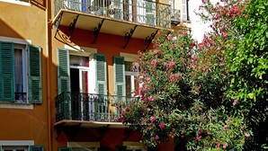 A building with balconies, green shutters, and a flowering bush. - Hotel Oasis (Nice)