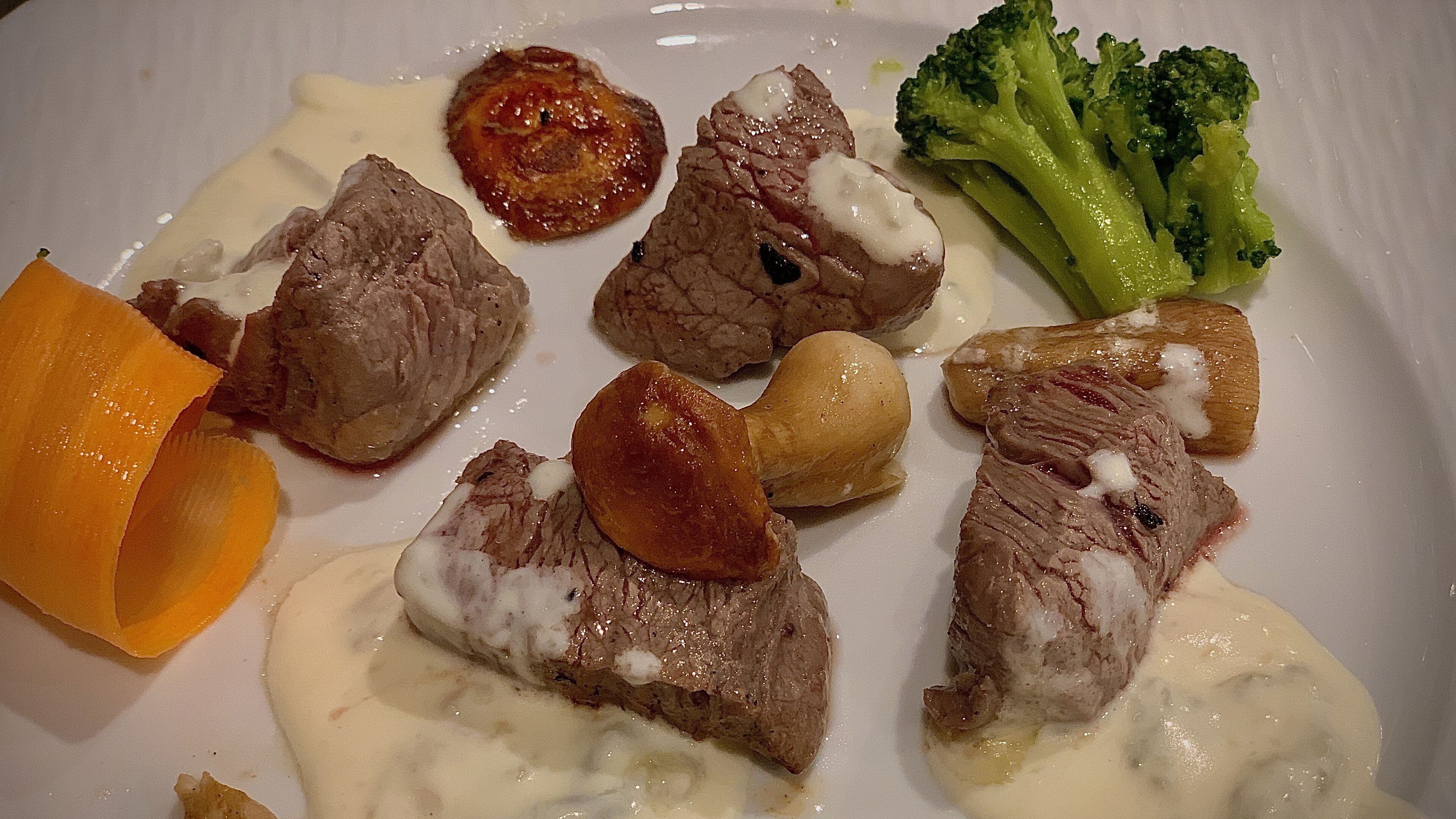 Un plato con rebanadas de carne, brócoli y una verdura anaranjada, posiblemente calabaza.