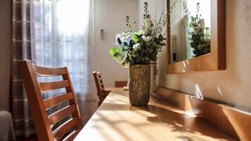 Un comedor con una mesa de madera, sillas y un florero.