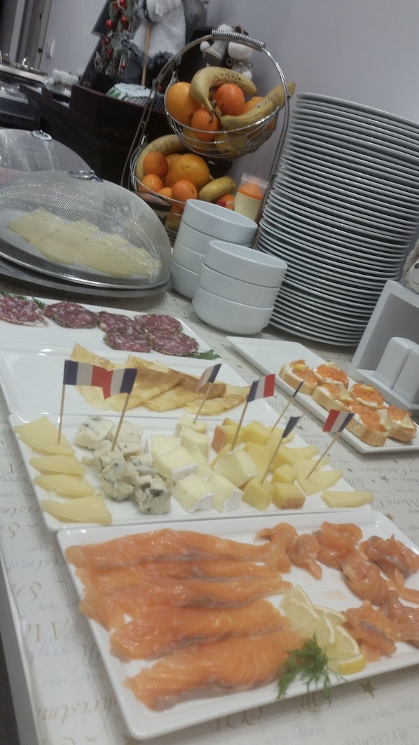 A buffet with various food items including salmon, cheese, and fruits. - Hotel Oasis (Nice)