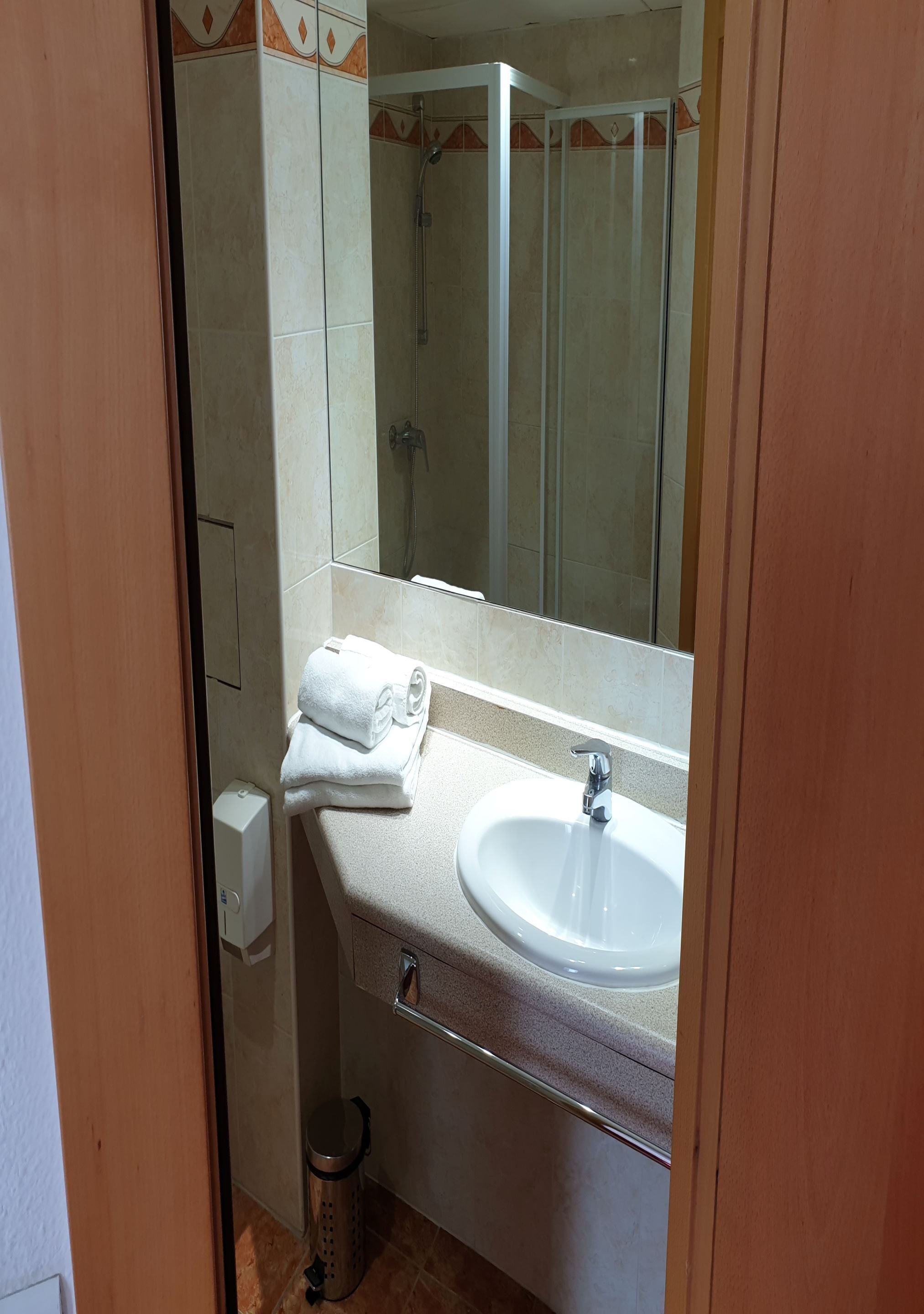 A bathroom with a sink, mirror, and shower.