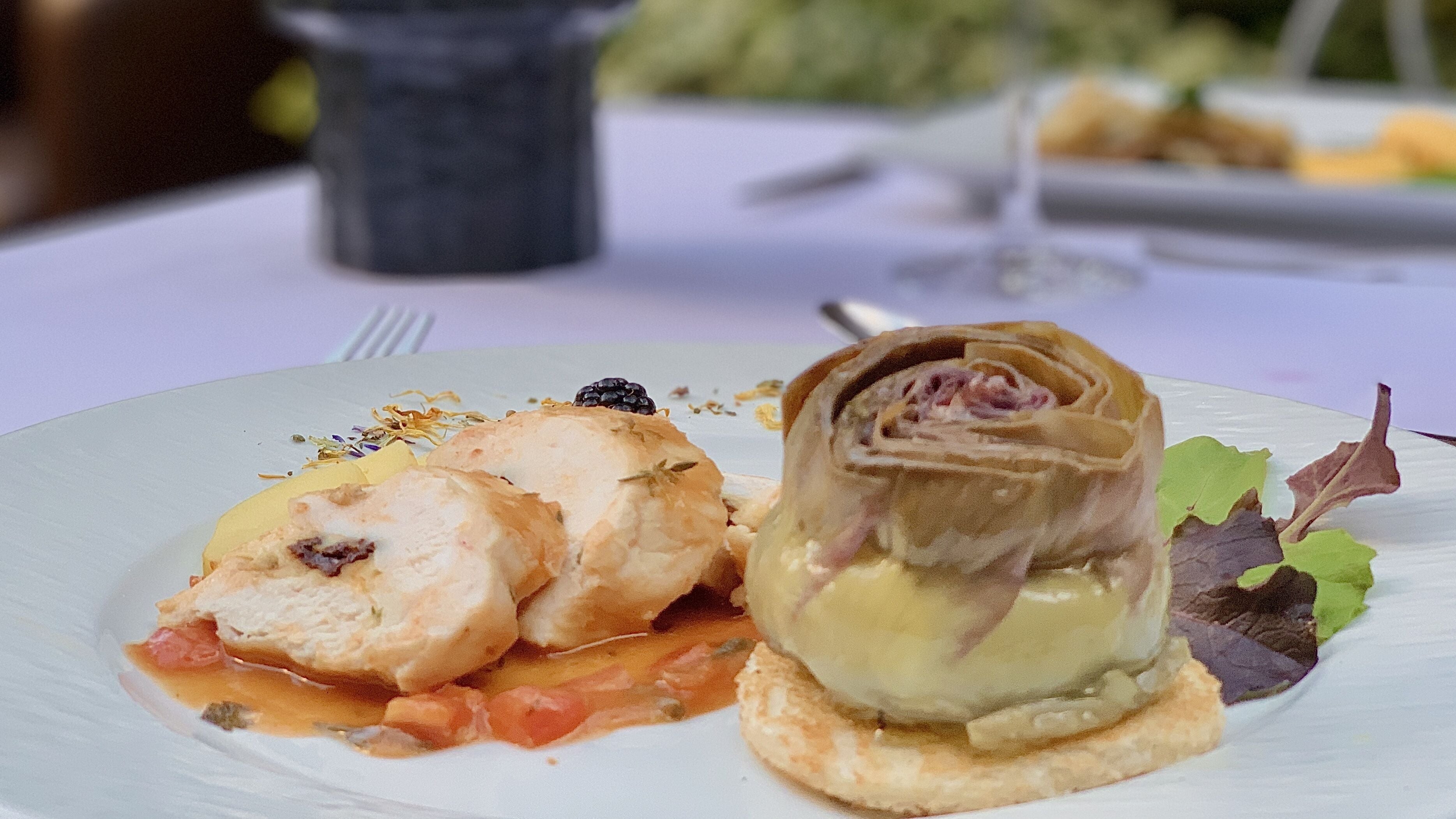 A plate with a rolled pastry and a piece of fish with sauce.