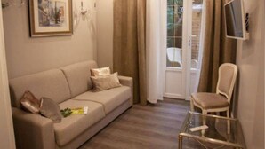 A modern living room with a sofa, a glass coffee table, and a chair. There is a sliding glass door leading to a balcony. - Hotel Oasis (Nice)